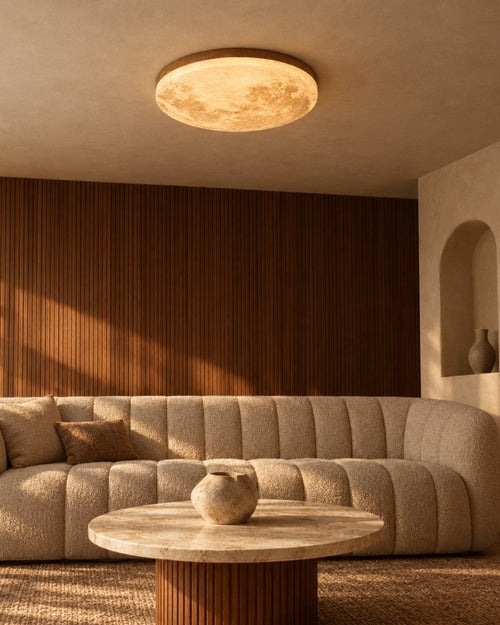 Erva ceiling light in warm walnut, lit above a sofa in a living room