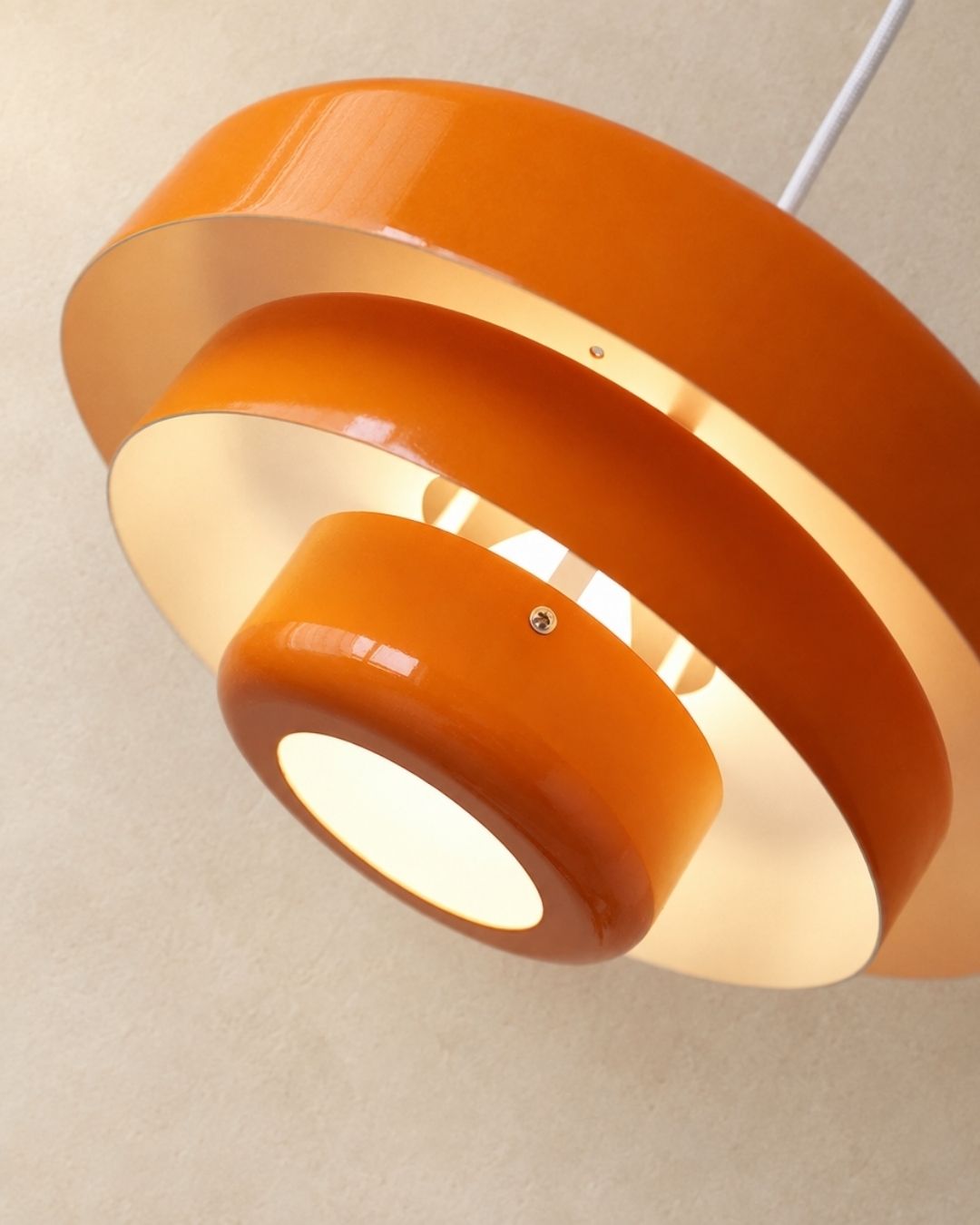 Tessia pendant light in orange, close view of the stacked iron tiers