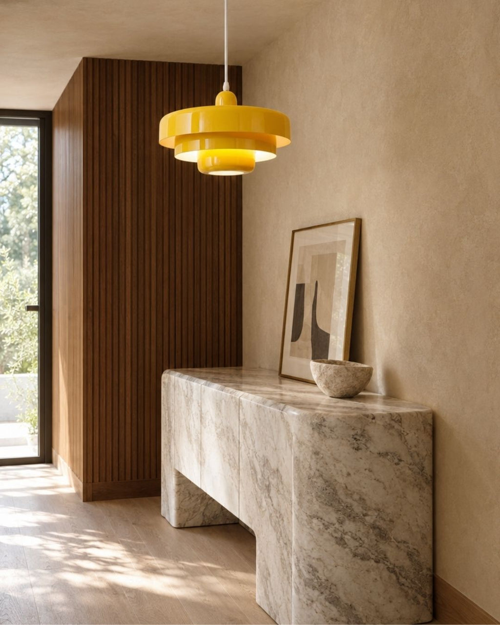 Tessia pendant light in yellow, hanging in a hallway above a marble table