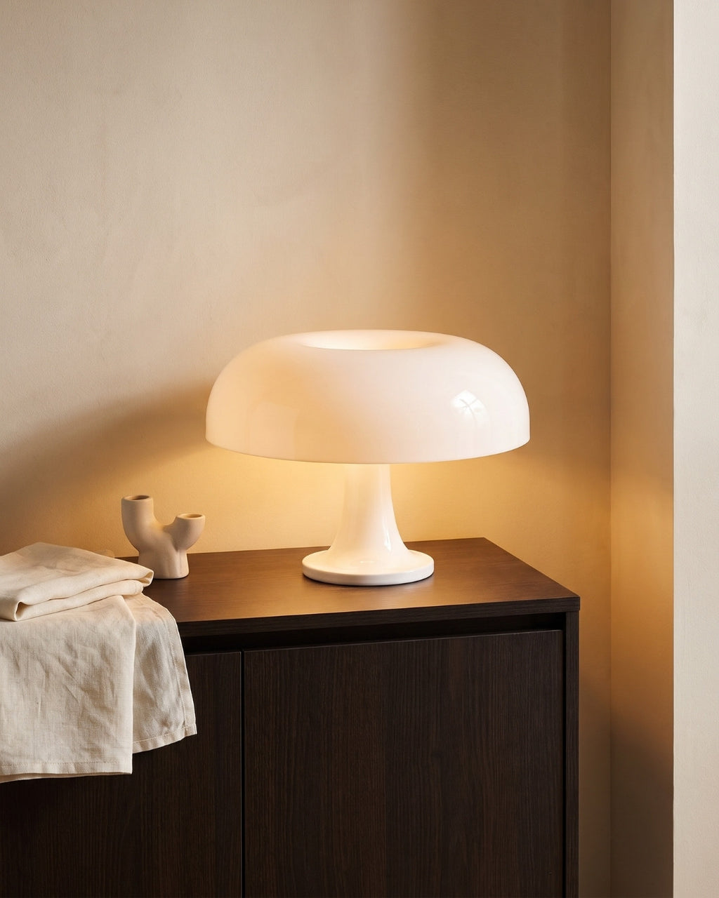 Beven table lamp in white lit on a sideboard in a living room