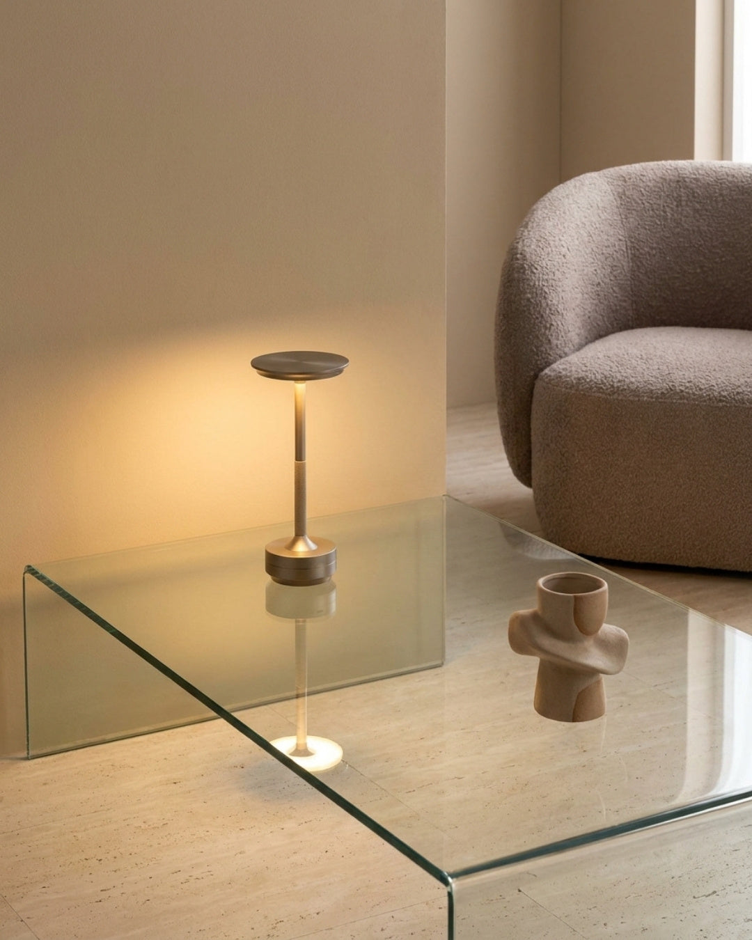 Brenna table lamp in silver lit on a glass table in a living room