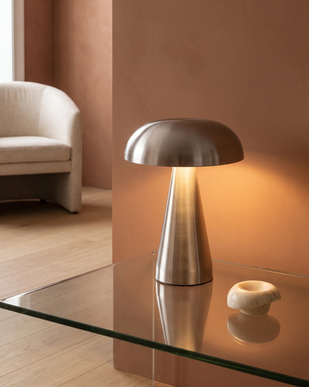 Cerlin table lamp in silver lit on a glass coffee table