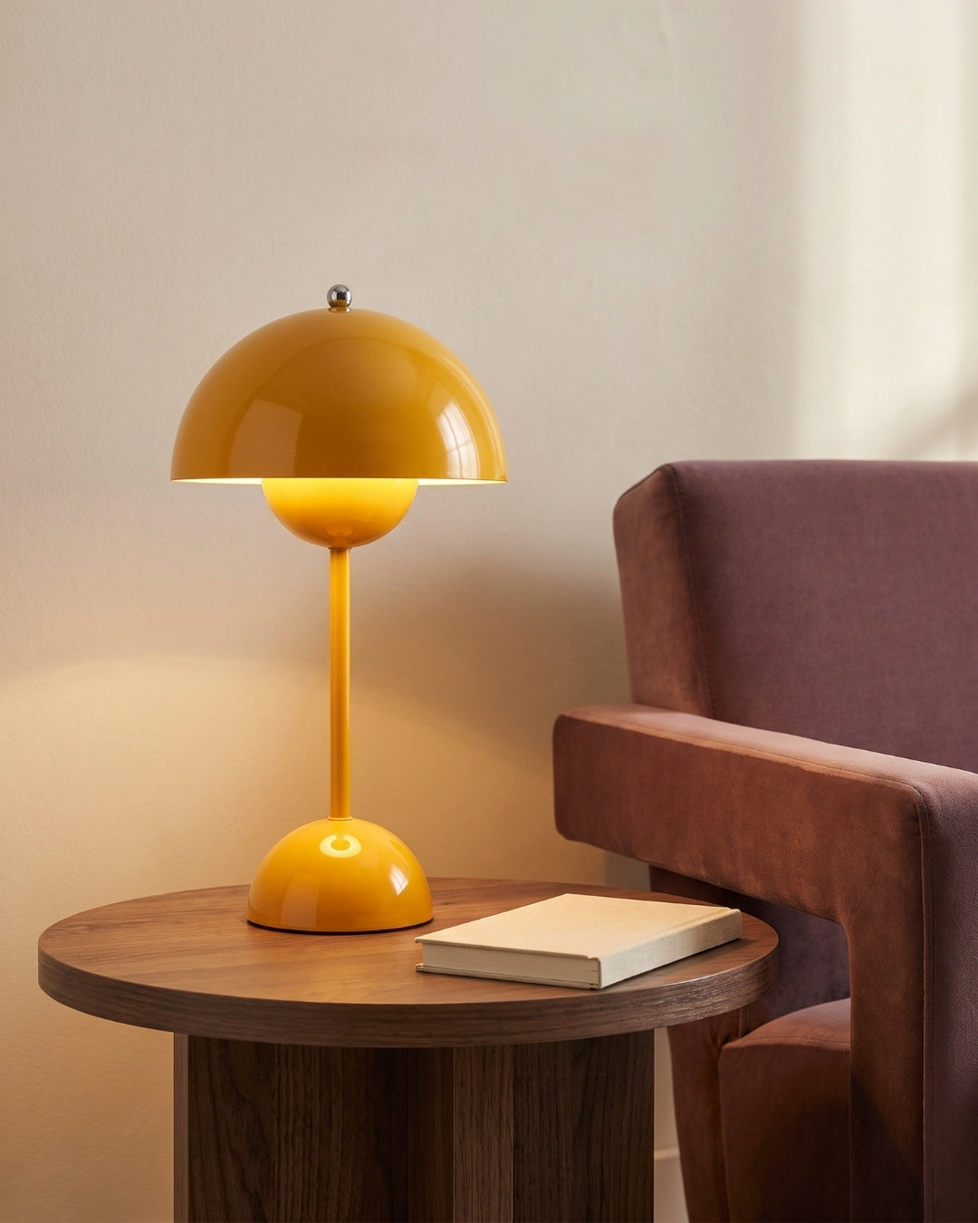 Elsin table lamp in yellow lit on a side table beside a book